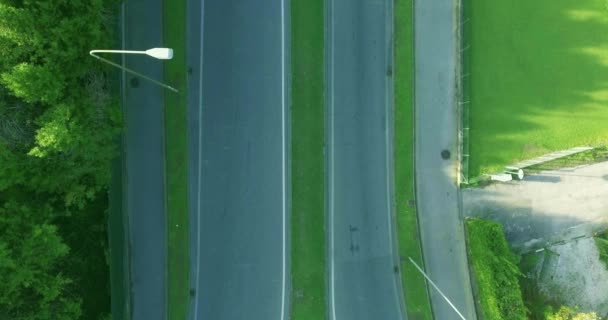 Estrada de asfalto com marcas de estrada e calçadas, carros em movimento, luzes de rua, tiro aéreo — Vídeo de Stock