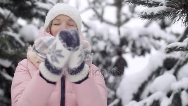 Активная молодая женщина в зимнем лесу хлопает в ладоши, тряся варежками от замедленного движения снега — стоковое видео