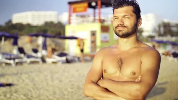 Deportivo hombre europeo despreocupado de pie en la playa mirando a la distancia disfrutando del sol y el mar. Movimiento lento — Vídeo de stock