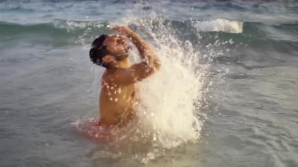 Брюнетка Человек выходит из моря выпрямляет волосы на заднем плане моря и волн. Медленное движение — стоковое видео