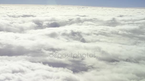 Vista general desde la ventana del avión durante un vuelo a nubes espesas y esponjosas. Un disparo aéreo. Viajar por aire — Vídeos de Stock