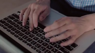 Konsantre kadın parmak metin, bir dizüstü bilgisayar kullanarak yer onun kucağına, oturma odasında rahat bir kanepede otururken, yukarı yatır