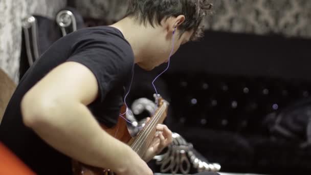 Guitariste masculin se réchauffe avant une performance musicale, joue une guitare électronique dans la chambre — Video