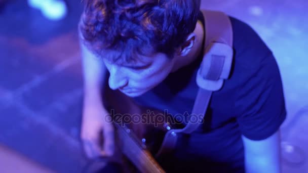 Guitarrista de uma banda de rock verifica o som da guitarra no palco, com a luz dos holofotes, indie rock, pop rock, show ao vivo — Vídeo de Stock