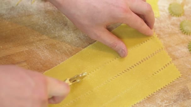 Типичный способ приготовления пасты в ресторанном кафе. Профессиональные роликовые ножи срезают полоски с тонкого листа теста, крупным планом, замедленным движением — стоковое видео