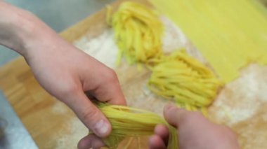 Ev yapımı makarna pişirme. Makarna yuvaya kıvrılıyor. Makarna un ile ahşap bir masa koymak. Ağır çekim. Yakın çekim
