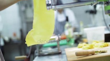 Şef hamur istimal makarna makine makarna için hazırlar. Arka plan iç restoran ya da kafe ve aşçı çalışması sırasında mutfakta. Ağır çekim