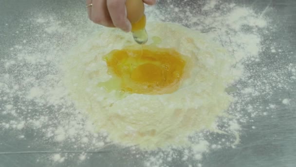 Manliga händer bryta ett rått ägg i mjöl. Degen förberedelse bearbeta Slowmotion, närbild. Ägget faller på en hög med mjöl — Stockvideo