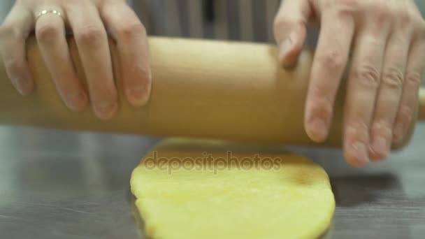 Le mani dello chef stendono l'impasto sul tavolo usando il mattarello al rallentatore primo piano — Video Stock