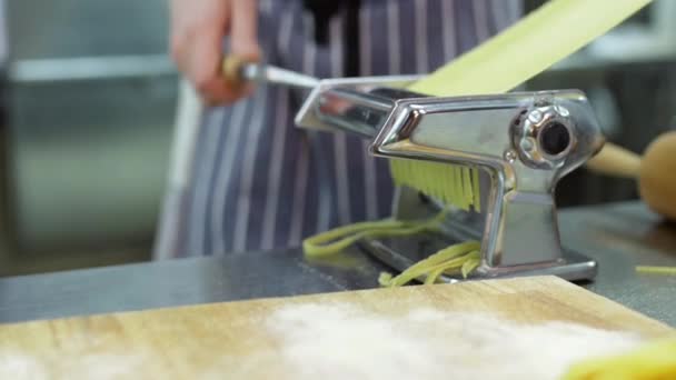 Chefs handen gebruiken een pasta snijmachine. Verse spaghetti pasta die uit de pasta machine komt close up — Stockvideo