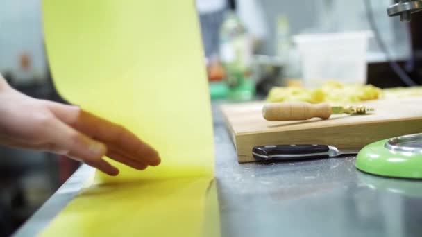 Szef kuchni Nanieś cienką warstwę ciasta przygotować makaron na stole. W tle kucharz w pracy w kuchni w restauracji lub kawiarni. Zwolnionym tempie — Wideo stockowe