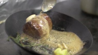 Yavaş hareket Şef kızartma baharat ve sarımsak, dökülen yağ sosu, kızartma tavası taze et biftekle bir kaşık kullanın. Yakın çekim