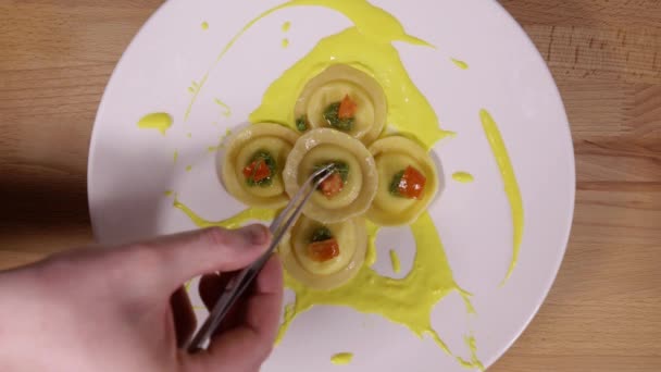 Αισθητικά όμορφο σερβίρισμα των πιάτων. Σεφ βάζει ένα κλαδάκι των Πρασίνων σχετικά με ραβιόλια, χρήση λαβίδας. Διακόσμηση στο πιάτο στο εστιατόριο πριν το σερβίρισμα — Αρχείο Βίντεο