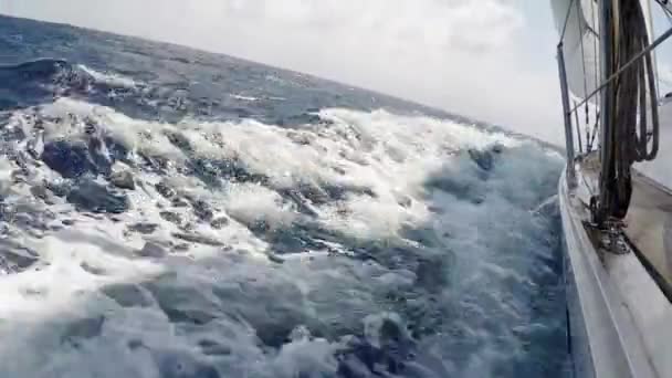 Iatismo no mar no dia de verão. Iate, barco navega em ondas azuis espumosas em alta velocidade — Vídeo de Stock