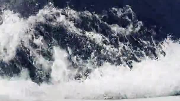 Skummande blå vågor slå på däcket på båten. Vatten spår bredvid båten — Stockvideo