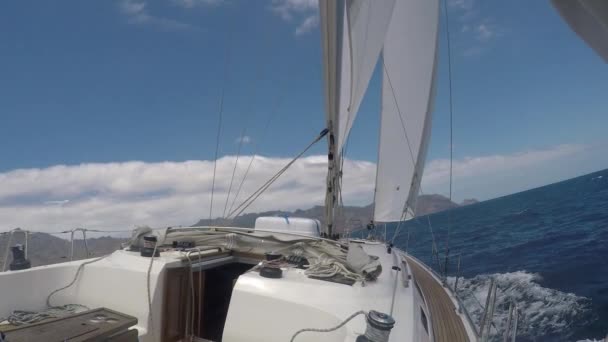 Vista da magnífica paisagem marítima com um iate à vela enquanto viaja, pontos de vista. Yacht flutua através de ondas azuis espumosas em alta velocidade — Vídeo de Stock