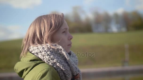 Porträtt av en ung vacker kvinna i en varm halsduk, njuter av en promenad i parken. Slow Motion — Stockvideo
