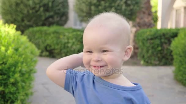 Sonriente niño europeo alegre camina en el parque en verano con buen tiempo, lento mo, primer plano — Vídeos de Stock