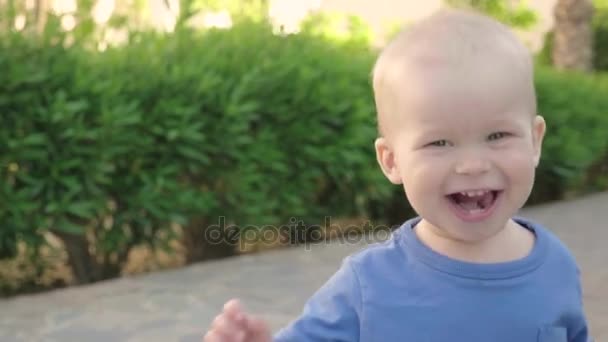 Retrato de un lindo niño rubio europeo alegre disfrutando de un paseo por un hermoso parque de verano, lento mo — Vídeos de Stock