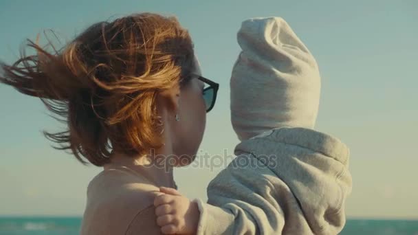 Travelers mother and son on the beach looking at the sea, rear view, close up, slow motion — Stock Video