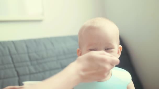 Slow Motion Cute beetje Europees schedel bij het ontbijt. Zorgzame moeder voedt haar zoon met een lepel — Stockvideo