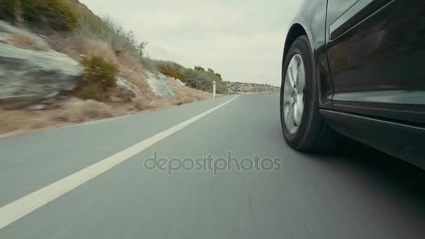 Movimiento del coche en una carretera en terreno montañoso. Ruedas de coche se mueve sobre un asfalto suave a alta velocidad — Vídeo de stock