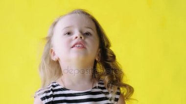 Sarı bir arka plan ağır çekim üzerinde uzun kıvırcık saçlı sevimli güzel küçük kız portresi