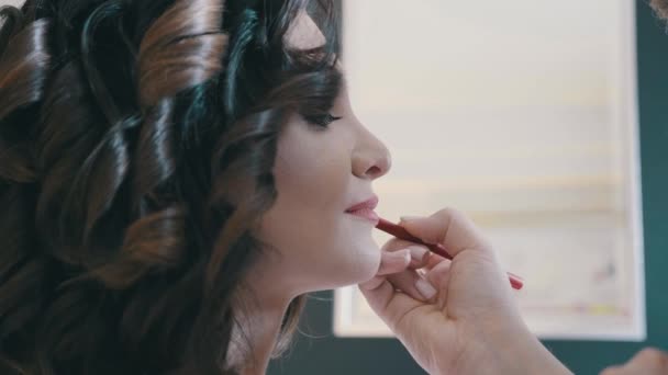 Lento MO maquillaje profesional artista rodea el contorno de los labios modelos con un lápiz, de cerca — Vídeos de Stock