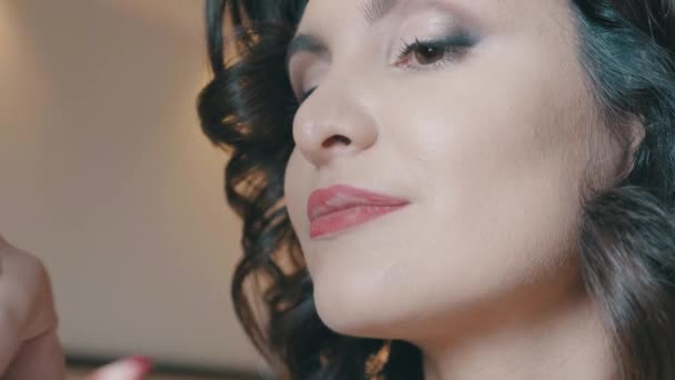 Slow motion lage hoek Professional stylist bezig met het creëren van een make-up voor een mooie jonge vrouw — Stockvideo