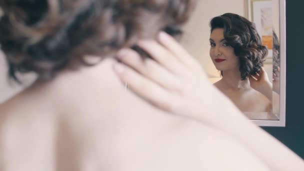 Гарна молода красива брюнетка захоплюється собою, сидячи перед дзеркалом, повільний рух — стокове відео