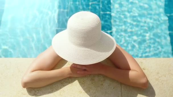 Close-up vacation relaxed woman in elegant white hat enjoying sunbathing at swimming pool — Stock Video