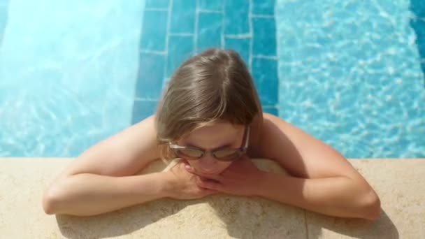 Attraktive braun gebrannte, entspannte blonde Dame mit Sonnenbrille, die sich am Swimmingpool sonnt — Stockvideo