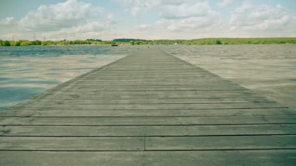 Lange oude grijze houten pier die zich uitstrekt tot kabbelend rivierwater — Stockvideo