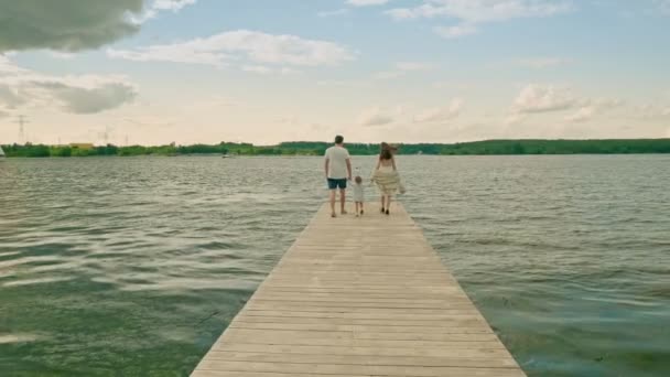 Mladí rodiče chodit spojující ruce s malou dcerou na molu — Stock video