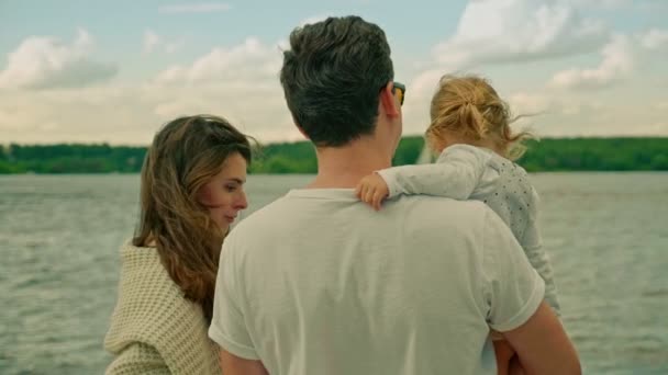Familia pareja con encantadora hija en papá brazos por río — Vídeos de Stock