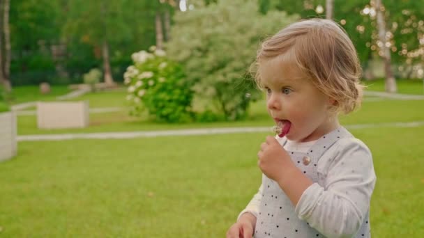 Menina loira cercada por bolhas de sabão lambe flor minúscula — Vídeo de Stock