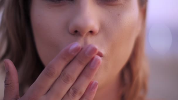 Extreme close-up sensuele vrouw lippen verzenden lucht kus met de hand glimlachen poseren op zonsondergang strand — Stockvideo