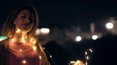 Close up festive millenial young girl dancing at outdoor party wrapped by garland lights