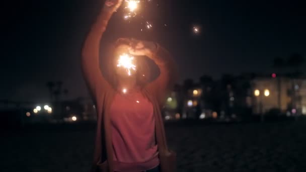 Mulher feliz dançando com sparklers na praia de areia da noite com emoção positiva à noite ao ar livre — Vídeo de Stock