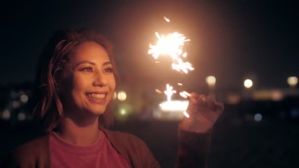 Close up positive female holding sparklers at night beach having fun girl looking on Bengal light — Stockvideo