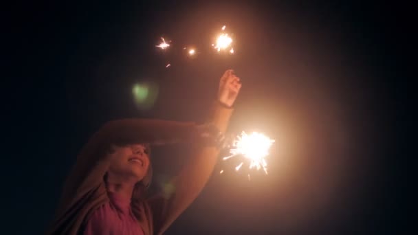 Adorable happy millenial woman playing with sparklers isolated at black studio background — Stockvideo