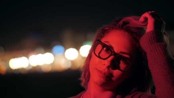 Лицо красивой тысячелетней стильной молодой девушки, играющей волосы, позирующие на открытом воздухе ночной вечеринки красный неон — стоковое видео