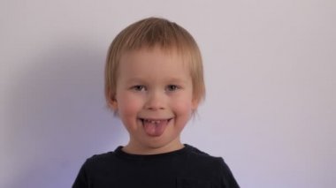 Portrait of funny little boy fooling showing tongue having positive emotion happy face expression