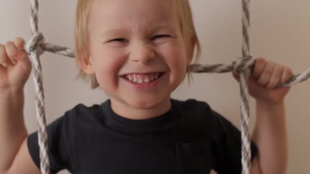 Close up face of laughing cute little boy posing on rope ladder having fun and positive emotion — ストック動画