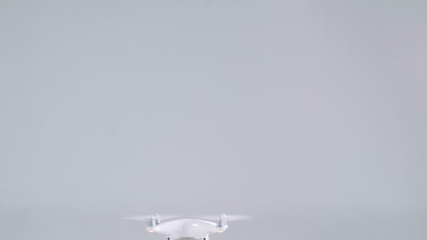 Active small white unmanned quadrocopter drone with action camera flying rising up at studio — Αρχείο Βίντεο