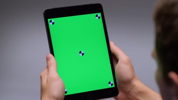 Man holding modern tablet pc looking on green screen close-up over the shoulder shot — Stockvideo