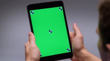 Over the shoulder shot male enjoying holding tablet pc making gesture flipping pages or surfing