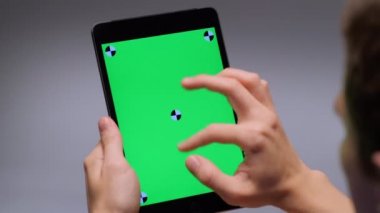 Over the shoulder shot man holding tablet pc making gesture flipping tape or surfing close-up