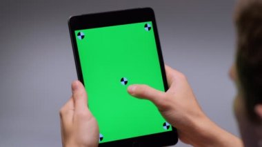 Man having good time looking on green screen of tablet pc touching touchscreen by finger
