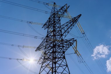 Elektrik direkleri ve çizgiler, izolatörler mavi gökyüzü güneş yoluyla.